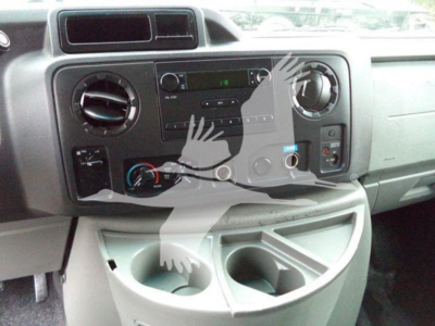 Ford E-450 dashboard showing radio, climate controls, and cup holders in front of center console.