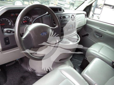 Ford E-Series interior showing steering wheel with Ford logo, dashboard, and front seats in a box truck cab.