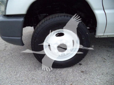 Ford E-Series van front wheel well and tire with white steel wheel visible in side view.