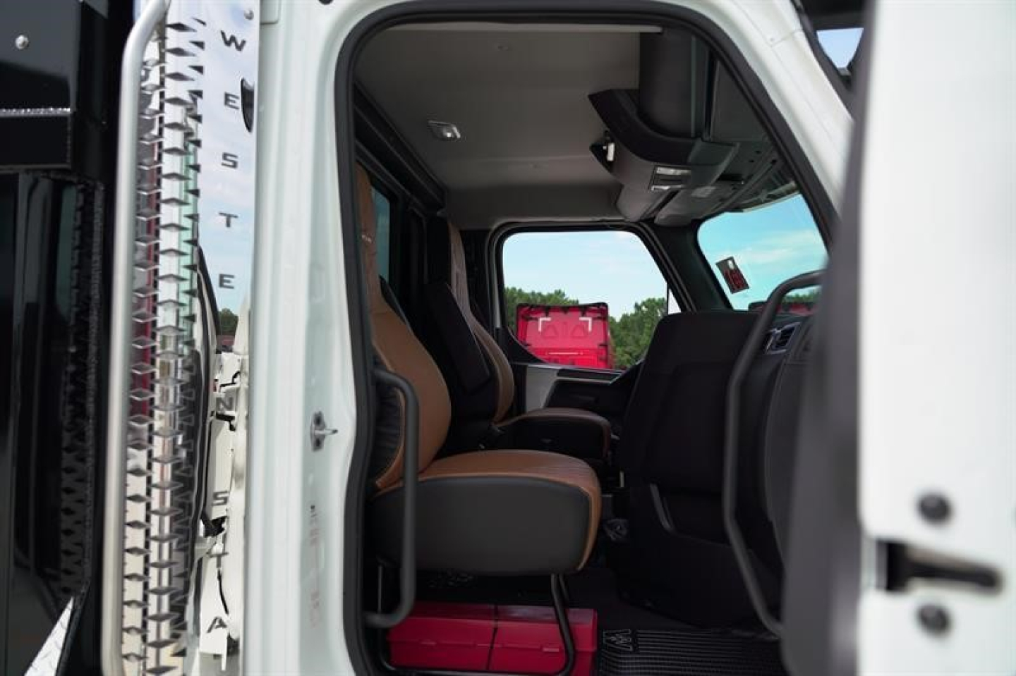 Interior of a new Western Star 47X dump truck cab showing front seats and dashboard view through the open door.