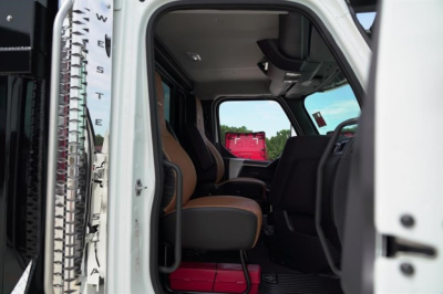 Interior of a new Western Star 47X dump truck cab showing front seats and dashboard view through the open door.