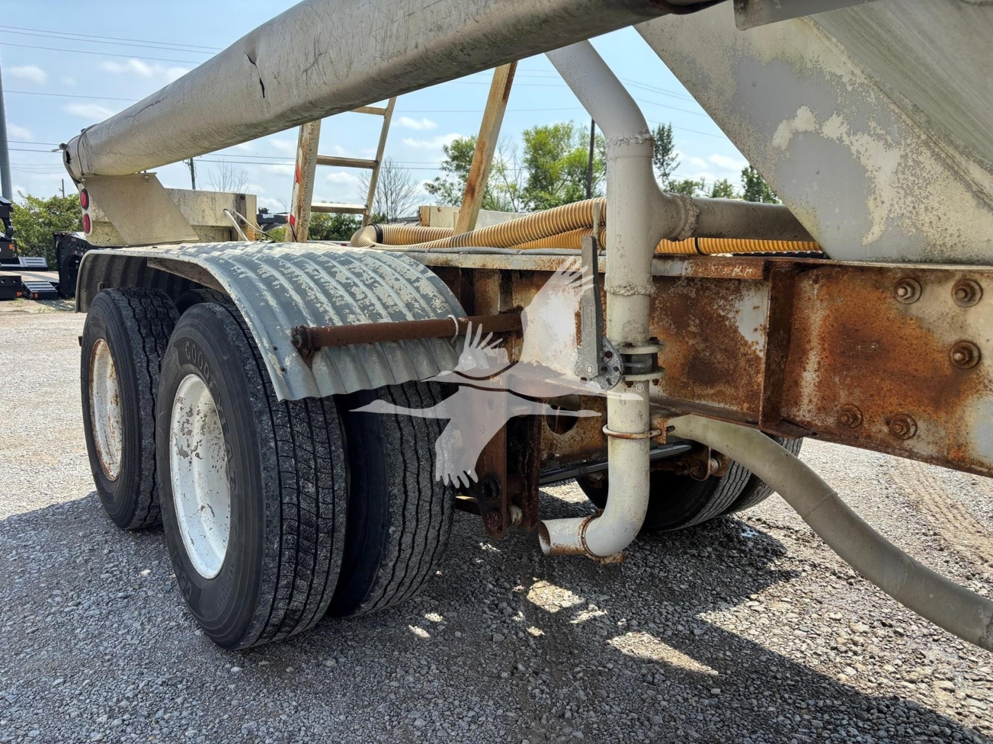 Fruehauf trailer undercarriage showing dual rear axles wheels and rusted frame with piping and support; part of a pneumatic-dry bulk trailer.