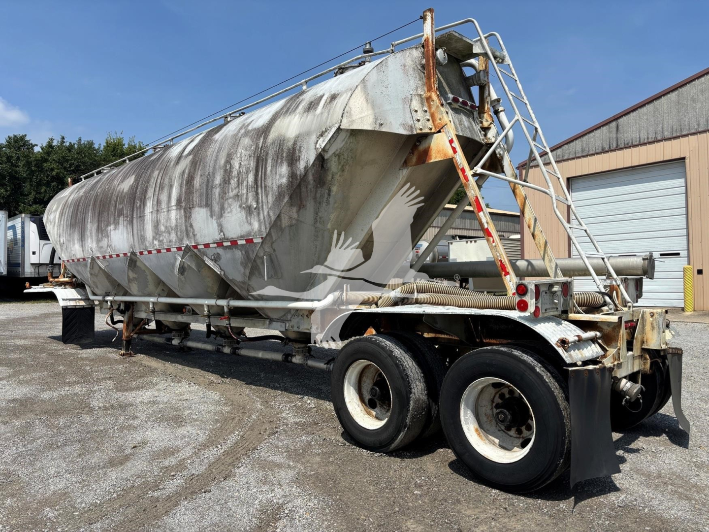 Fruehauf 1980 pneumatic dry bulk trailer showing rear ladder and dual rear axles with weathered aluminum tank.