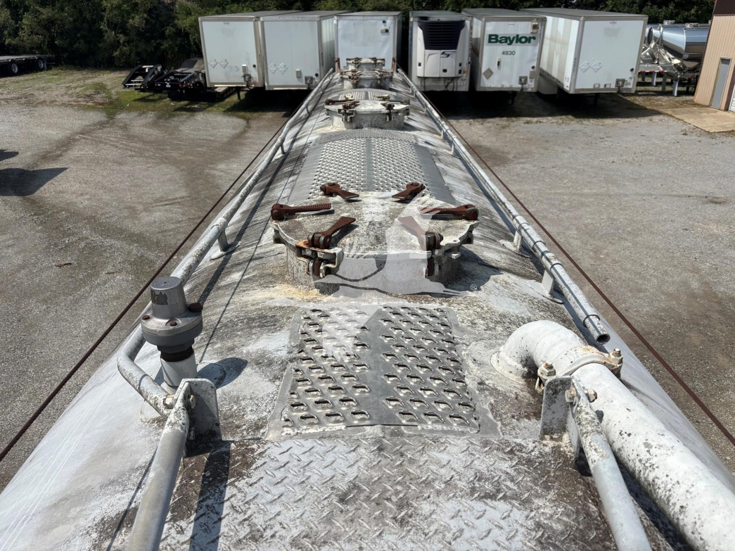 Fruehauf pneumatic dry bulk trailer top deck with access hatches and metal diamond plate, worn surface texture visible