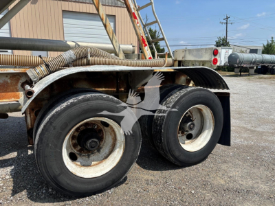 Fruehauf pneumatic dry bulk trailer axles and wheels with metal fenders and hoses, showing side view of dual tires and part of frame.