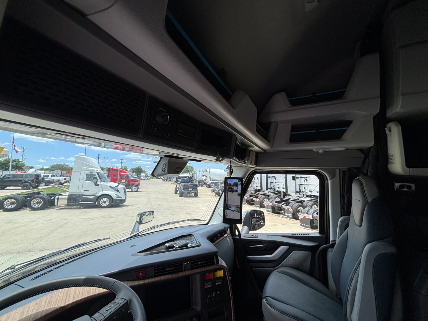 Volvo VNL64T860 (cab interior) showing steering wheel, dashboard, and driver seat with side mirror view through windshield