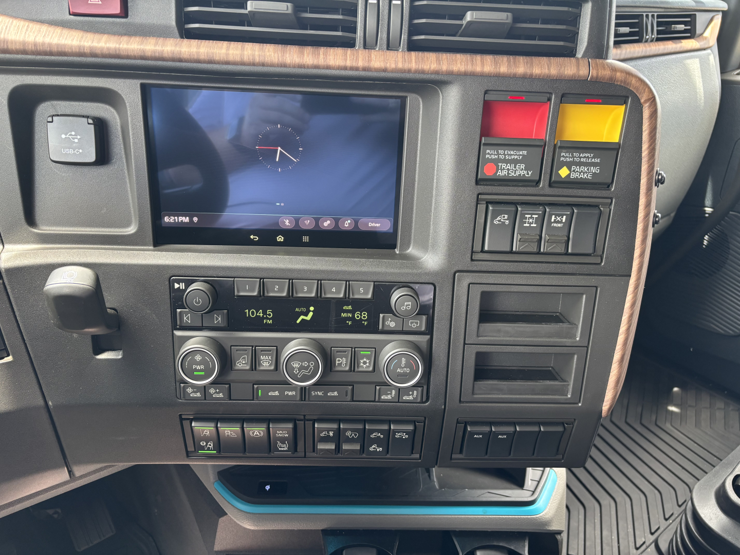 Truck dashboard panel showing navigation display, climate controls, and warning lights in a Volvo VNL cabin.