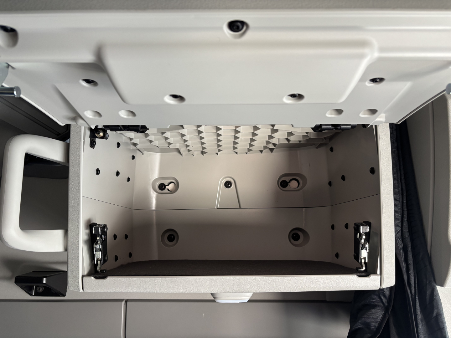 Storage drawer inside the Volvo VNL64T860 cab with multiple mounting points and a metal mesh above; no visible text on the drawer.