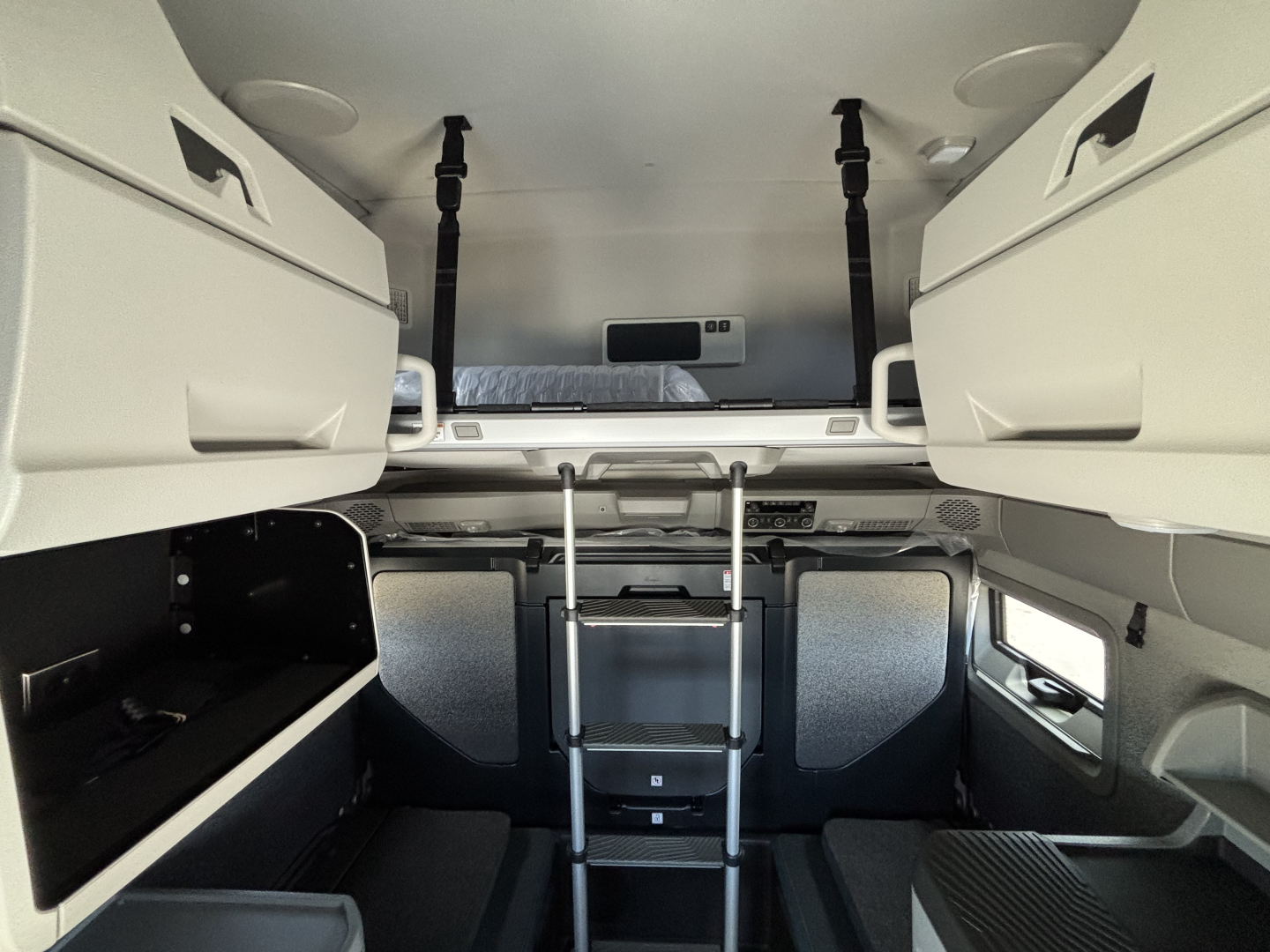 Volvo VNL64T860 sleeper cab interior showing upper bunk with ladder, side storage compartments, and ladder supports.