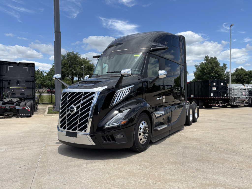 2027 Volvo VNL64T860 conventional sleeper truck with chrome grille, black body, shining mirrors, parked in lot.