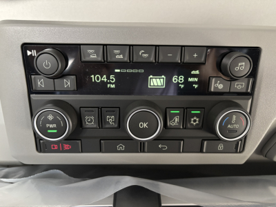 Truck cab radio and controls panel showing 104.5 FM, 68°F, settings buttons, OK button, and climate controls.