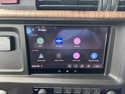 Volvo VNL64T860 cabin interior showing infotainment display with Android Auto icons and apps, woodgrain dash trim, HVAC vent.