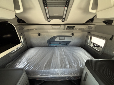 Volvo VNL64T860 sleeper cab interior showing bed with plastic cover, overhead storage, and side window; dashboard and controls not visible.
