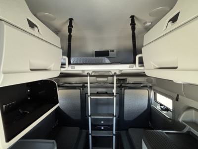 Volvo VNL64T860 sleeper cab interior showing upper bunk with ladder, side storage compartments, and ladder supports.