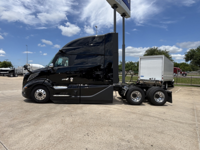 Volvo VNL64T860 truck in black, side view showing sleeper cab, side mirrors, and dual rear axles with chrome wheels.