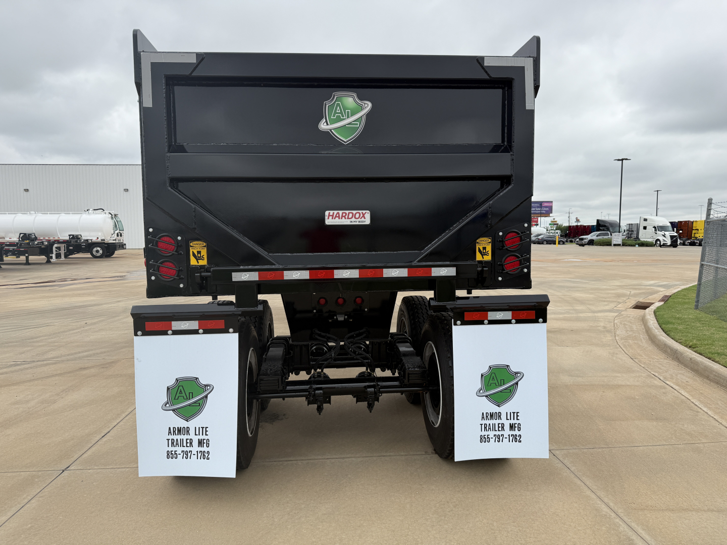 Dump trailer rear showing Armor Lite SHD32/48 with black body and green logo, Mud flaps with Armor Lite text, rear lights, and license plate area.