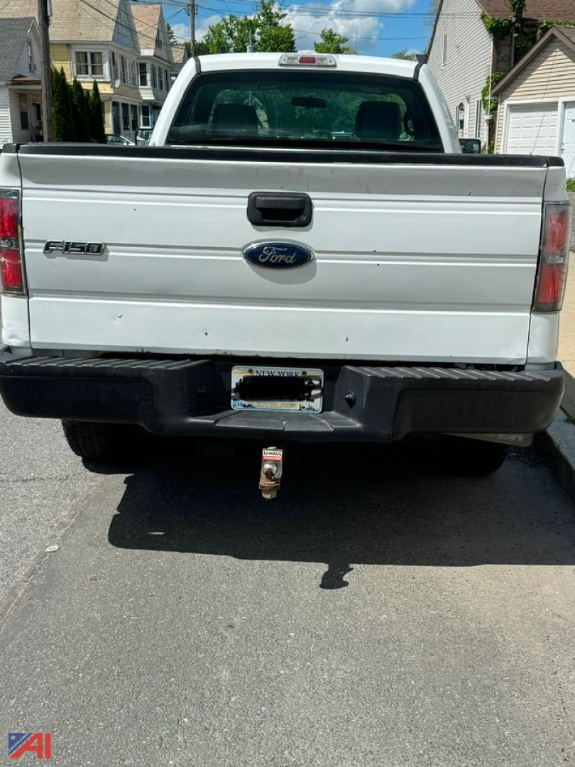 Rear view of a white 2013 Ford F-150 pickup truck showing tailgate with Ford emblem and F-150 badge, tow hitch, and 4x4 bumper.