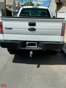 Rear view of a white 2013 Ford F-150 pickup truck showing tailgate with Ford emblem and F-150 badge, tow hitch, and 4x4 bumper.