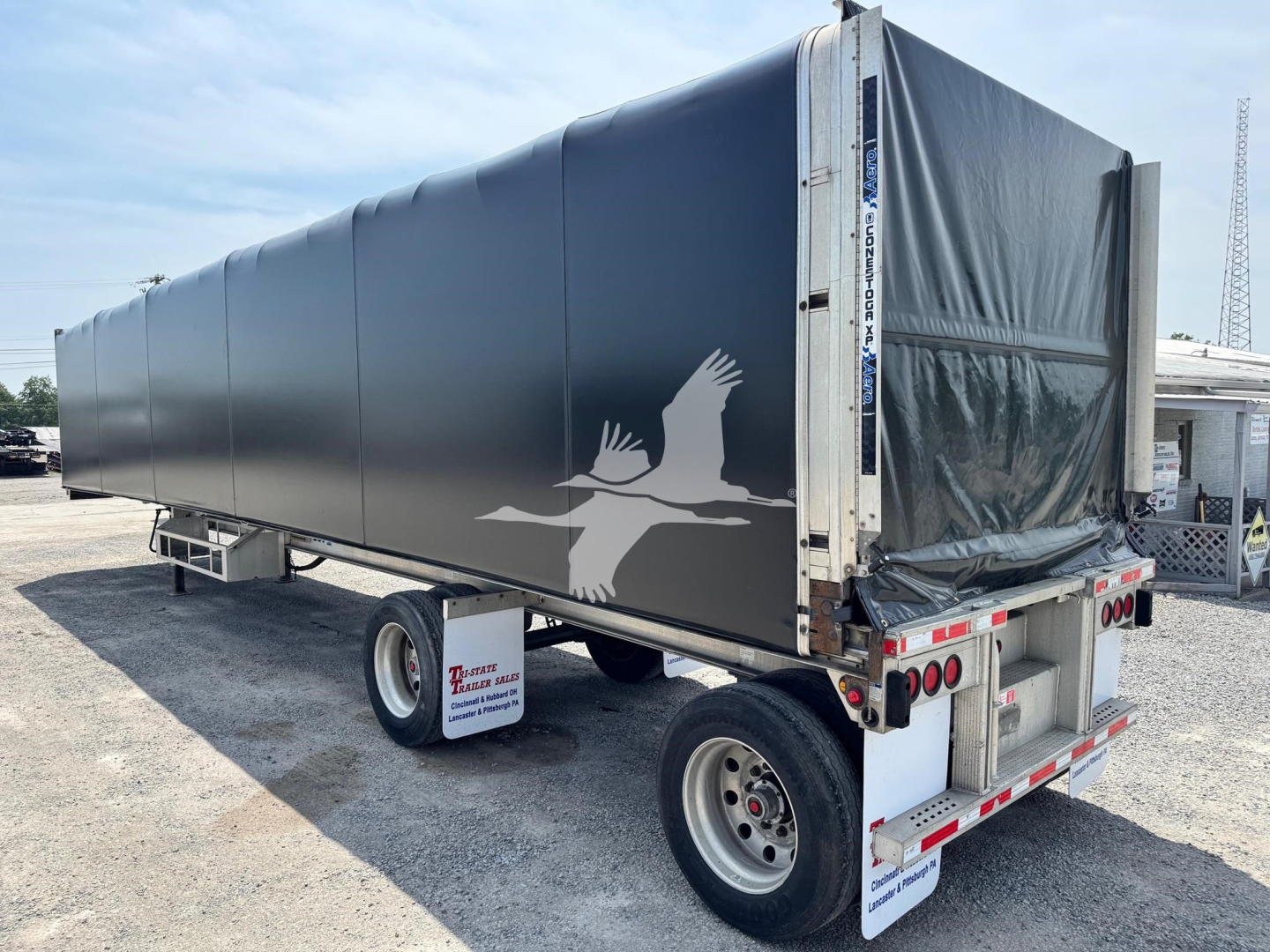 Trailer showing aluminum flatbed curtainside with gray tarpaulin rear and white eagle graphic on side.