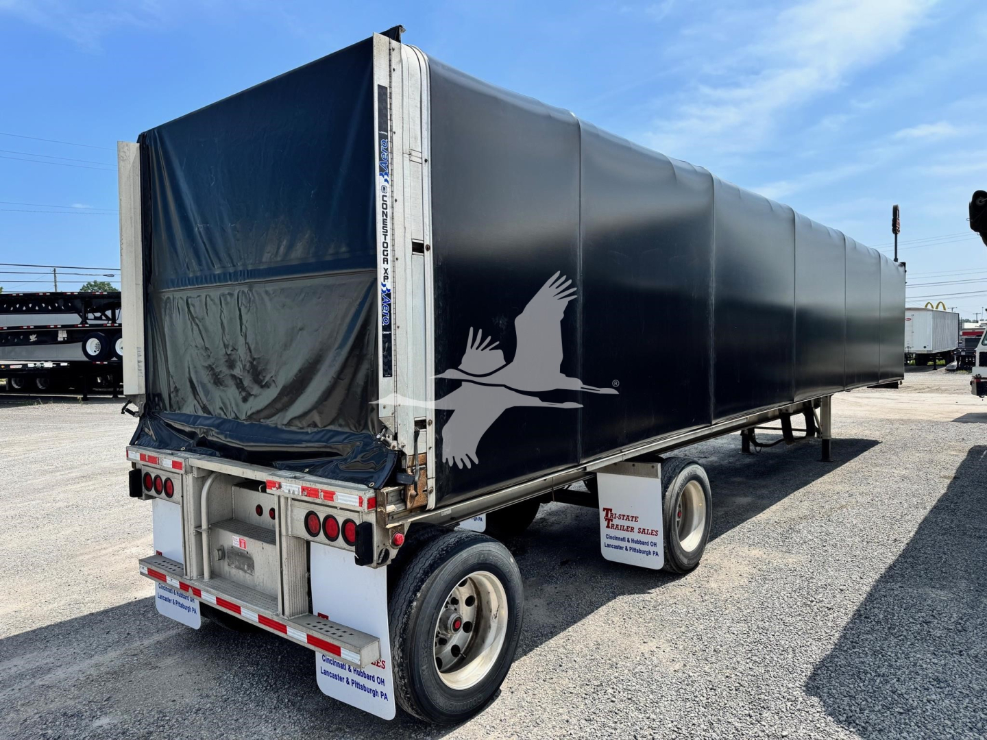 Used 2019 East aluminum flatbed curtainside trailer with black tarp and white bird logo on side, rear view showing lights and bumper.