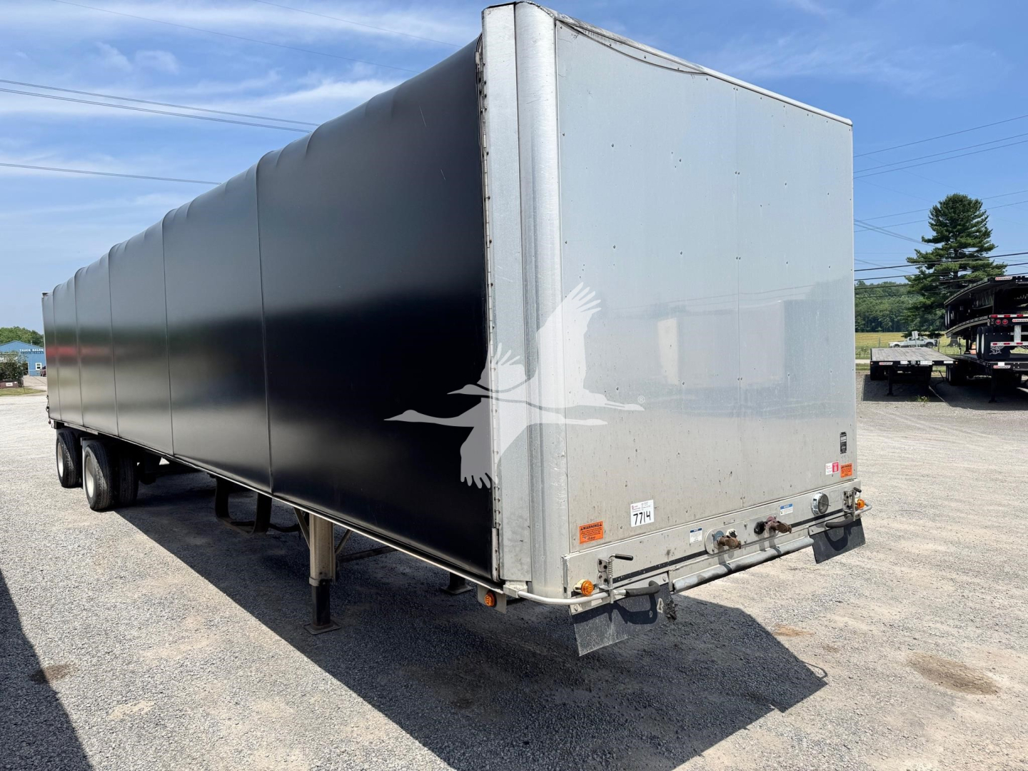 Trailer rear and side view of a used 2019 aluminum flatbed Curtainside trailer with black paint, dual rear doors, and mounted taillights.
