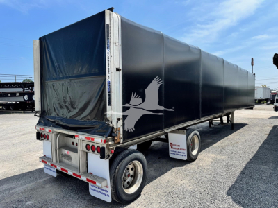 Used 2019 East aluminum flatbed curtainside trailer with black tarp and white bird logo on side, rear view showing lights and bumper.
