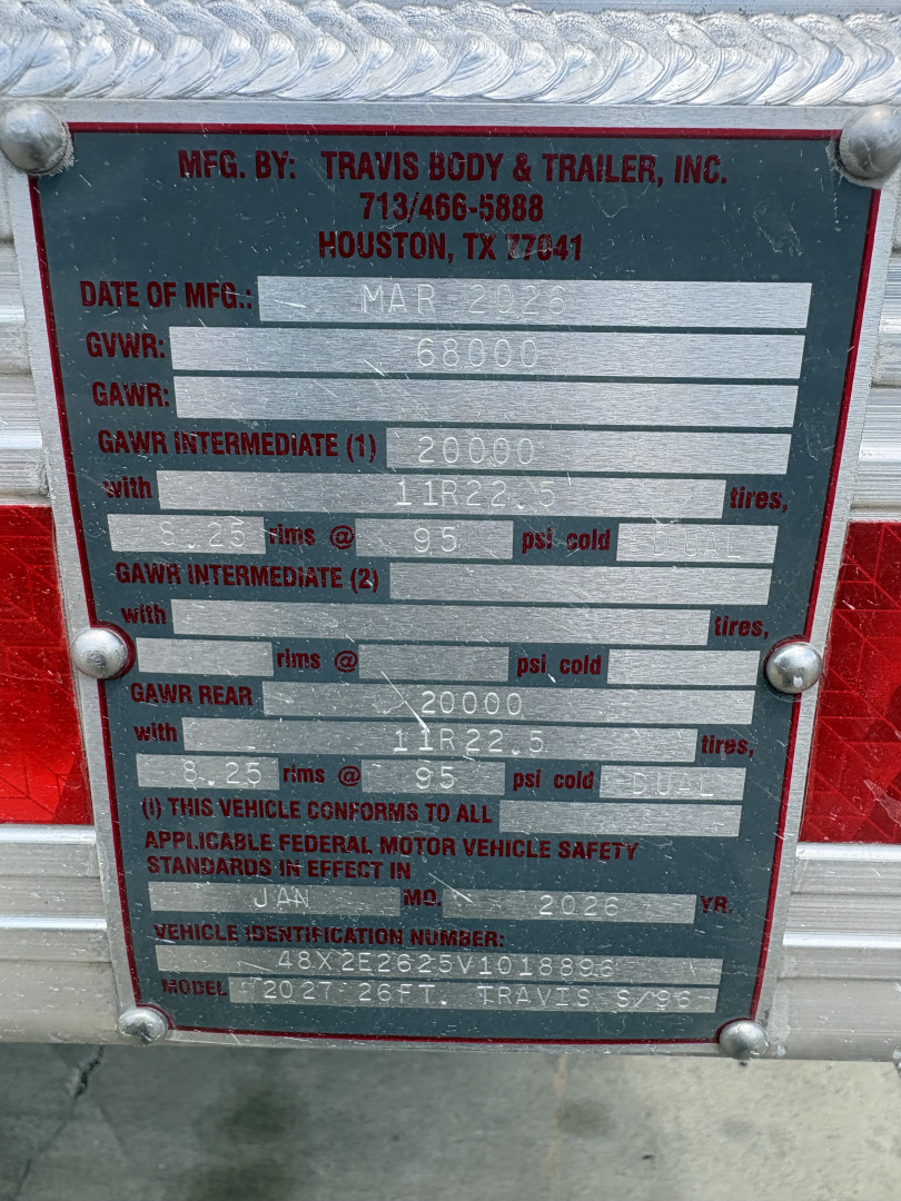 Plate on Travis End Dump trailer showing manufacturing by Travis Body & Trailer, Inc. with GVWR 68000, GAWRs, tire specs, VIN 48X2E2625V1018896, and model 2027 Travis S/LT.