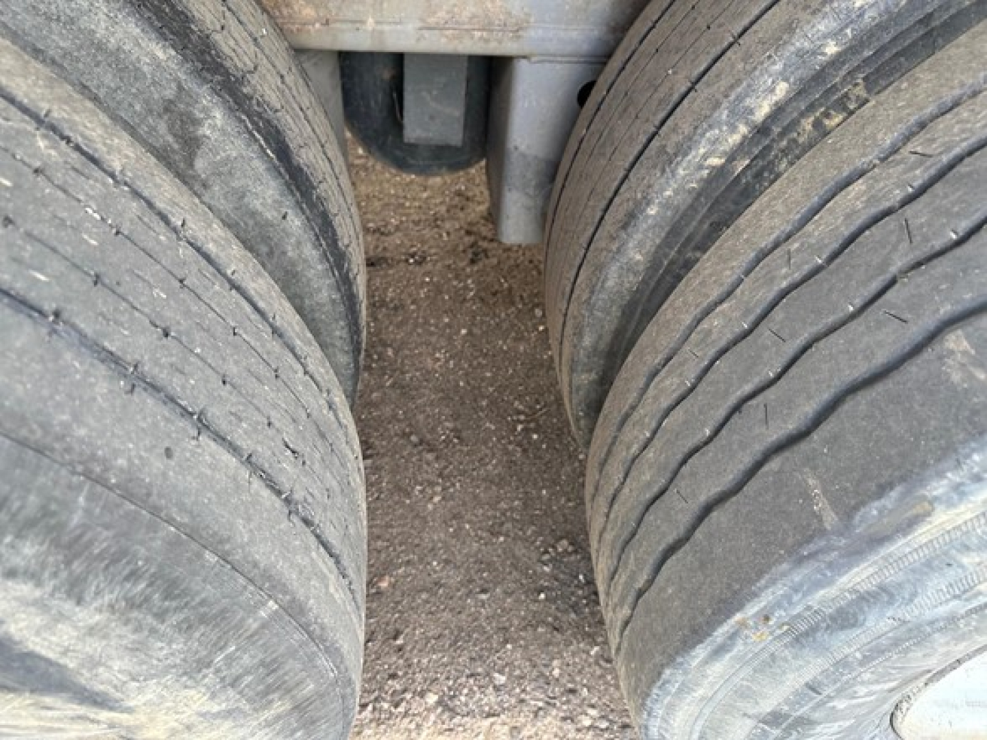 Trailer axle pair view showing dual heavy-duty tires on Clark Steel flatbed trailer, with dirt/grime on tires and wheel area.