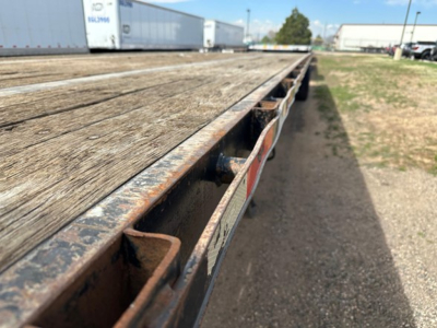 Flatbed trailer edge with wooden deck showing metal side rails and a weathered surface.