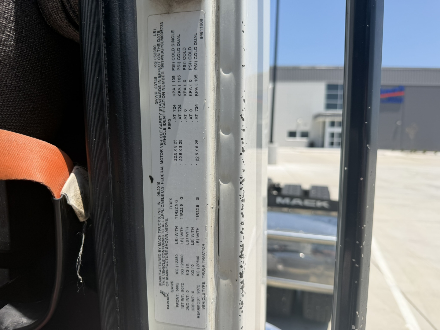 Mack PI64T cab interior door area showing door jamb sticker with vehicle specs and VIN sticker.