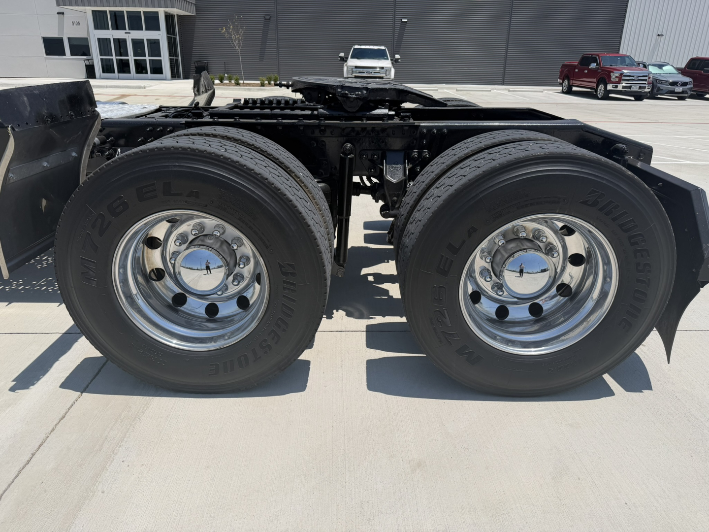 Dual rear tires mounted on a Mack PI64T tractor chassis showing chrome wheel rims and Bridgestone tires, fifth wheel receiver visible, side rails and frame in view.