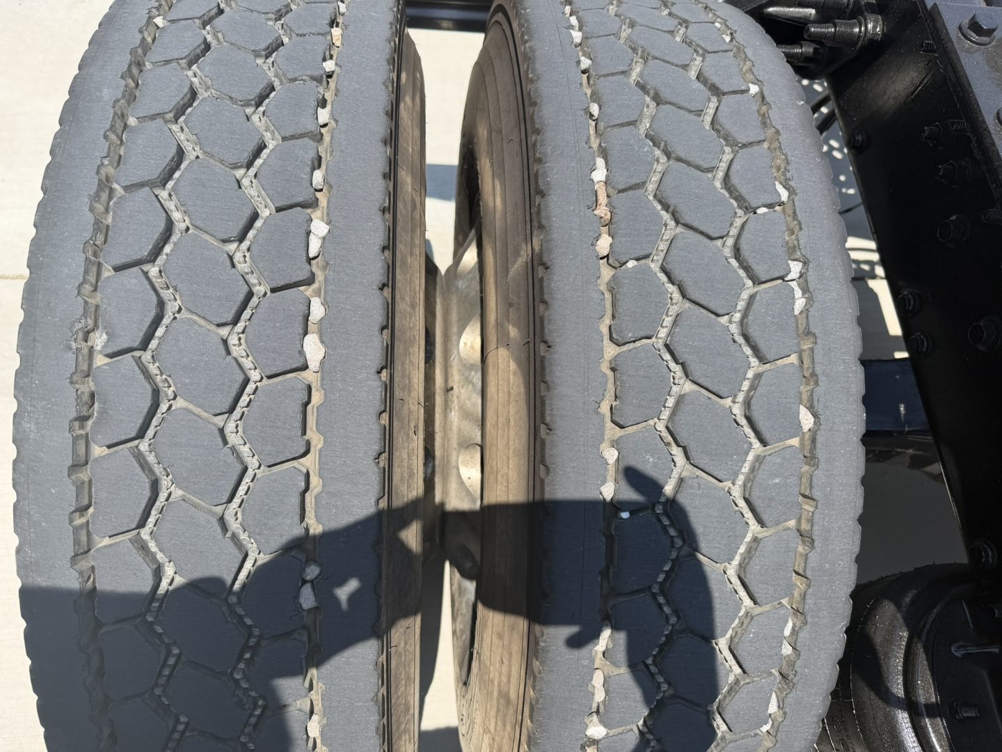 Twin rear truck tires with visible tread pattern on a Mack PI64T truck chassis, showing wheel hubs and surrounding frame.