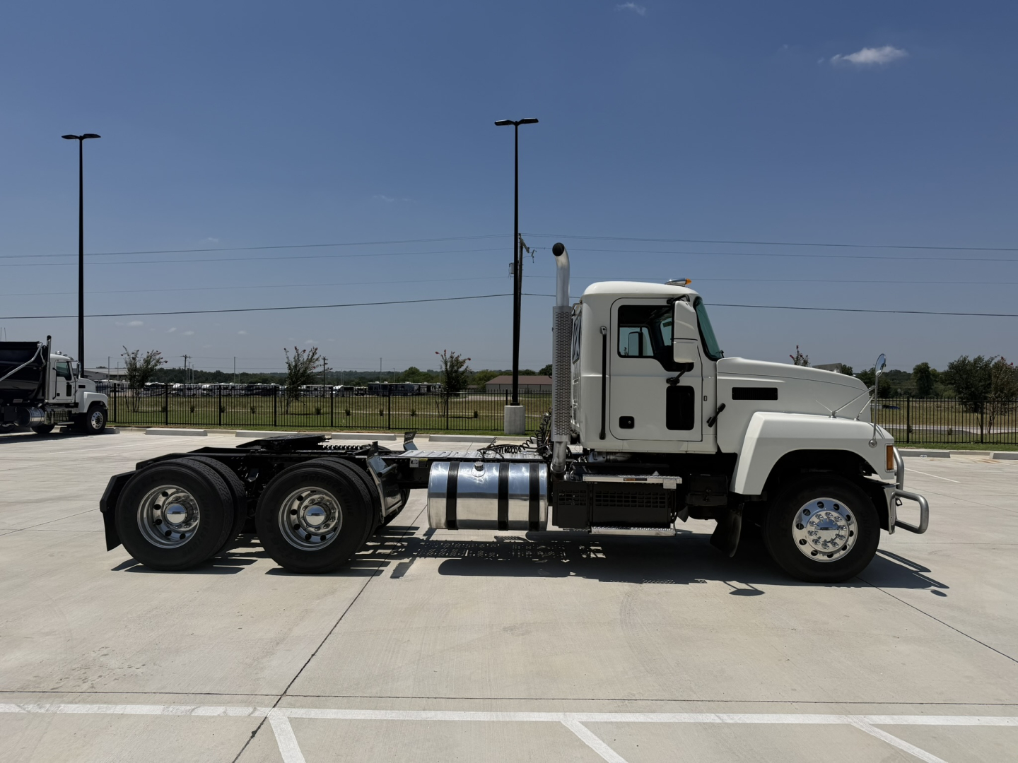 Truck side view showing 2020 Mack PI64T conventional daycab with 6x4 tandem rear axles, cab, fuel tanks, and exhaust stack.