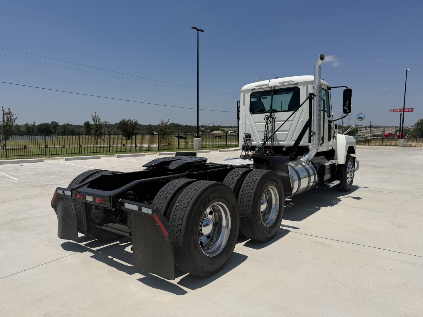 Mack PI64T daycab tractor rear-three-quarter view showing chassis and dual rear axles, fifth wheel, and exhaust stacks.