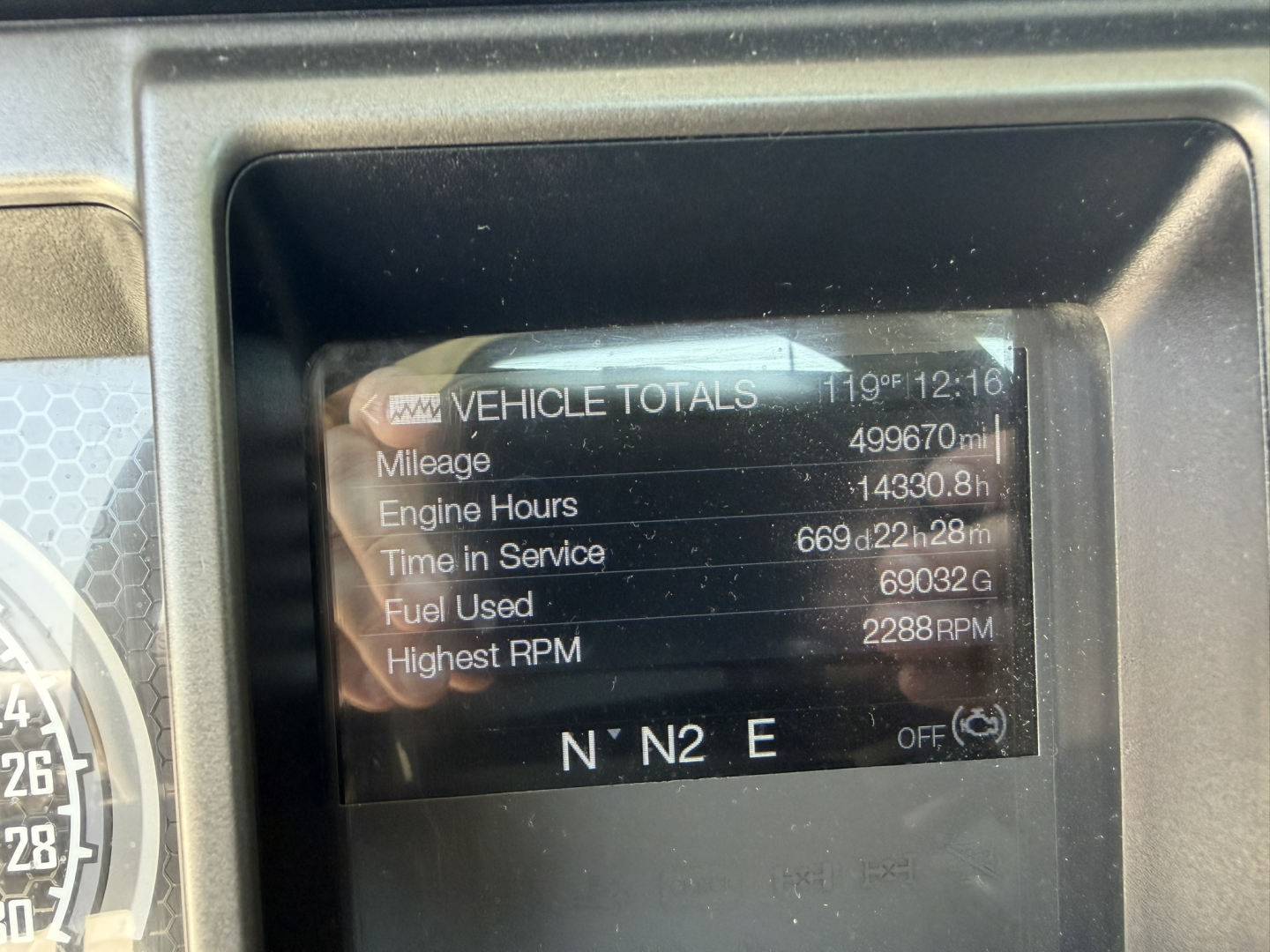 Vehicle totals display showing mileage 499670 mi, engine hours 14330.8 h, time in service 6692d? 28m, fuel used 69032, highest RPM 2288 RPM, compass N N2 E. Dashboard screen in Mack PI64T truck.