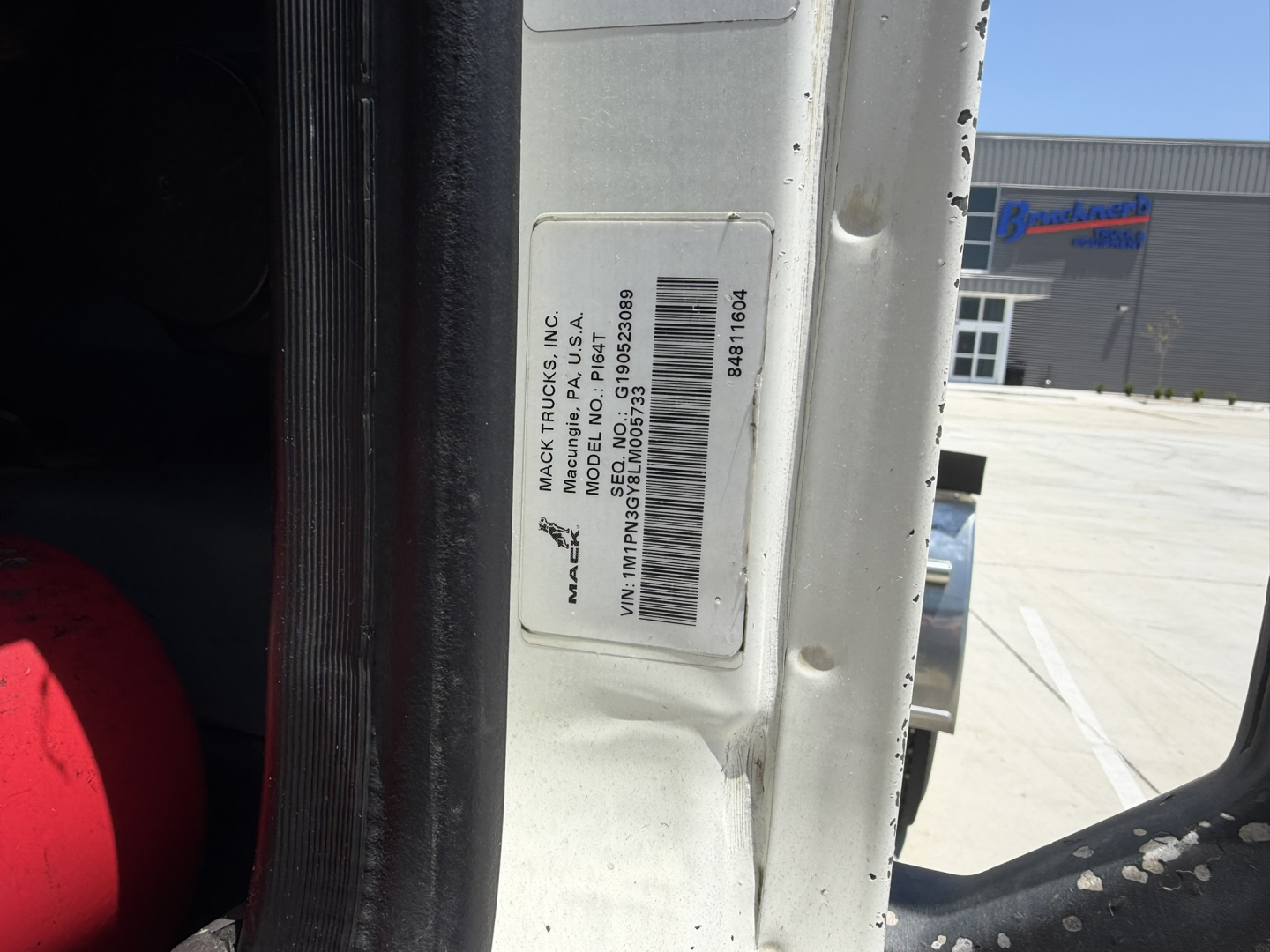 Truck door jamb with VIN sticker and barcode for a 2020 Mack PI64T conventional daycab, showing vehicle identification details and stock number B3696P.