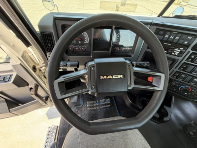 Mack PI64T truck cockpit steering wheel with dashboard controls and MACK emblem, view from driver seat.