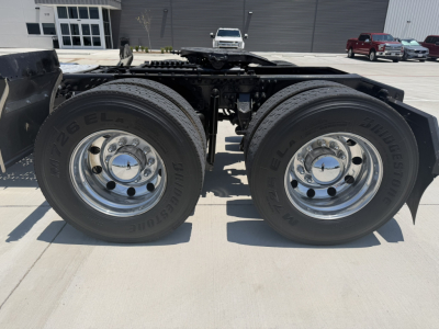 Dual rear tires mounted on a Mack PI64T tractor chassis showing chrome wheel rims and Bridgestone tires, fifth wheel receiver visible, side rails and frame in view.
