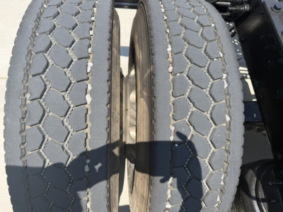 Twin rear truck tires with visible tread pattern on a Mack PI64T truck chassis, showing wheel hubs and surrounding frame.