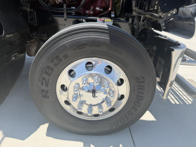 Truck wheel and Bridgestone tire on Mack PI64T daycab showing R2835 and tire tread details.