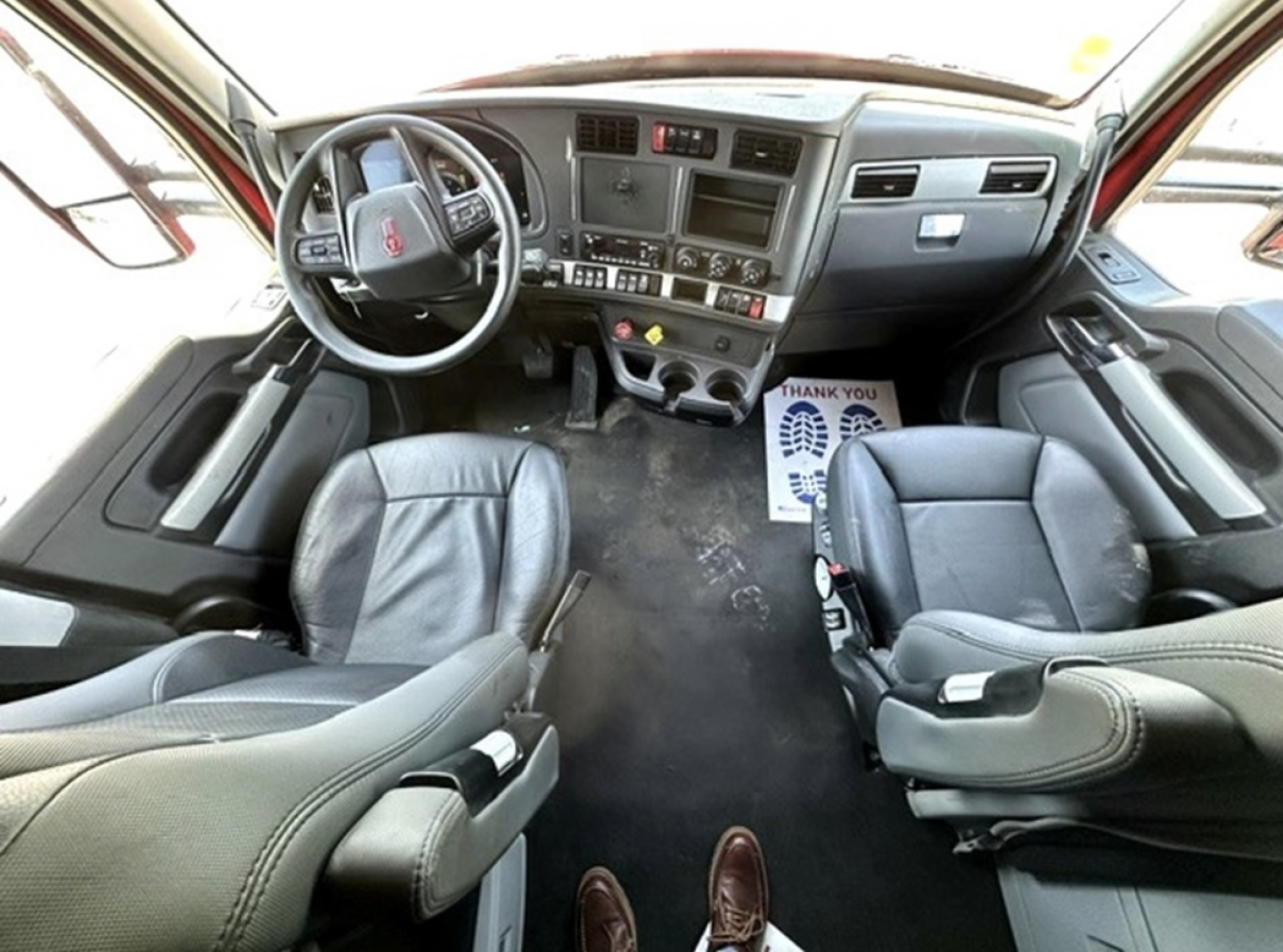 Truck cab interior of a 2022 Kenworth T680 showing steering wheel, dashboard, and front seats.