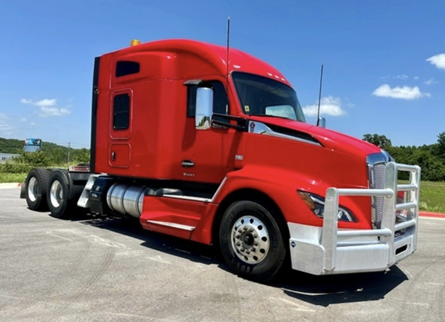 Kenworth T680 conventional sleeper truck in red, front and side view showing chrome bumper guard and dual rear axles.