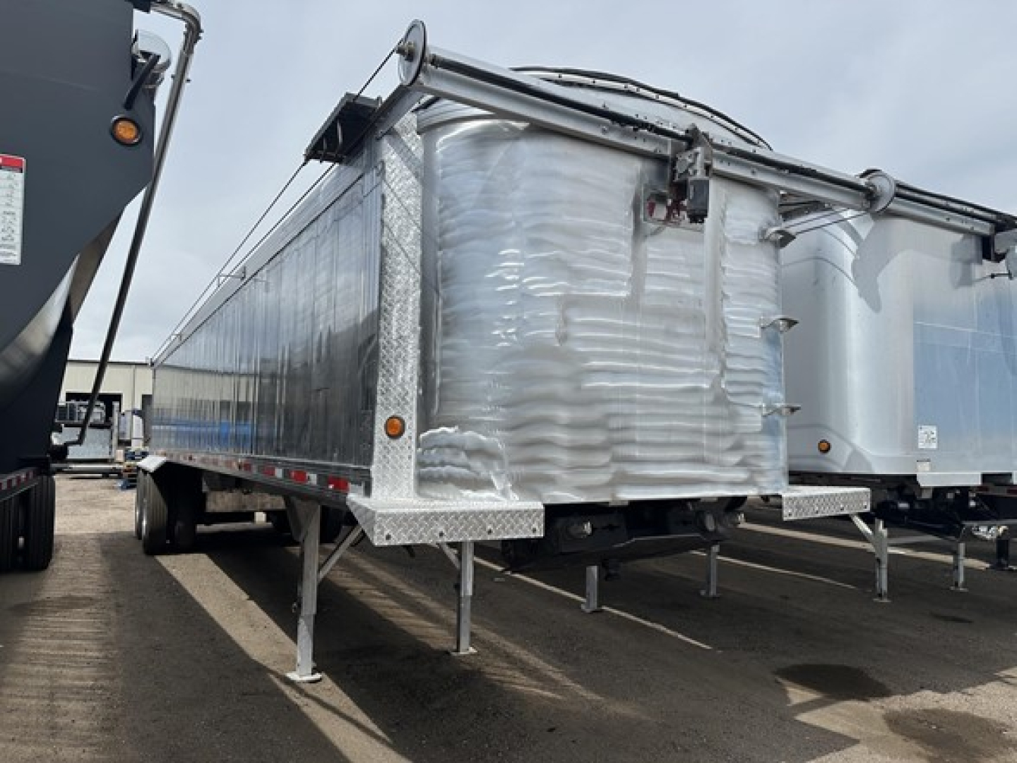 2018 Travis Vertex dump trailer side view showing aluminum conveyor-dented front corner and support legs.