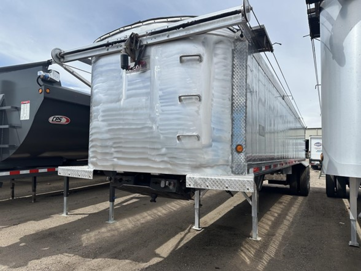 Dump trailer showing rear and side views with aluminum diamond plate and folded tarp mechanism.