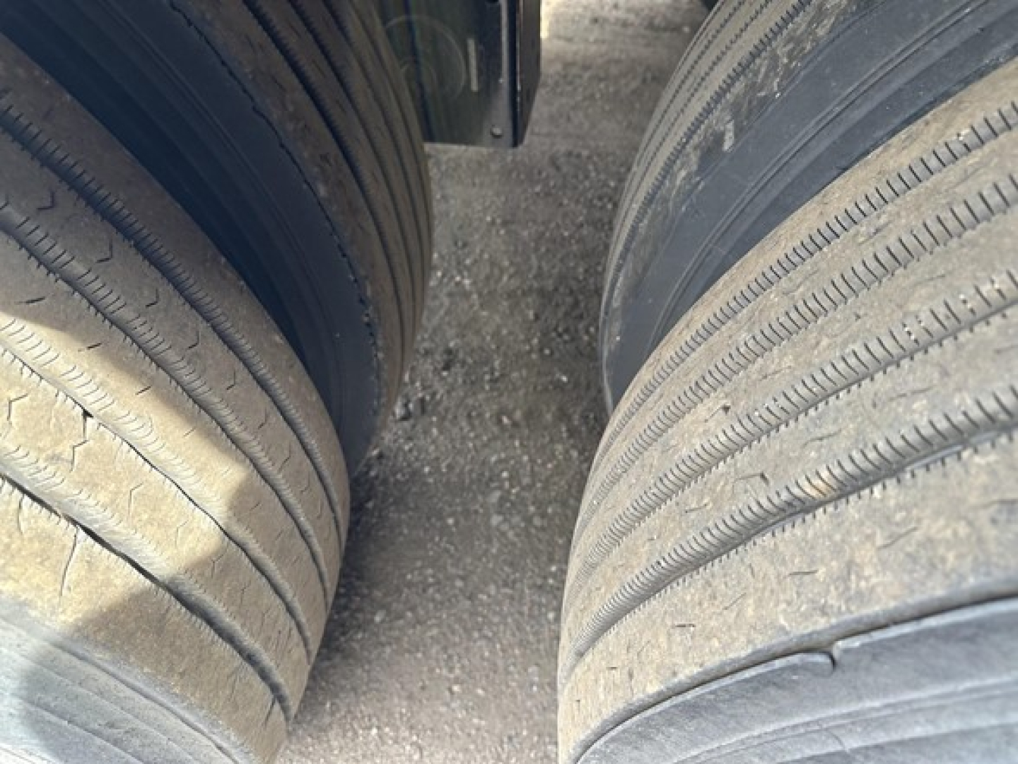 Truck trailer tires with tread visible showing wear pattern and gap between dual wheels.
