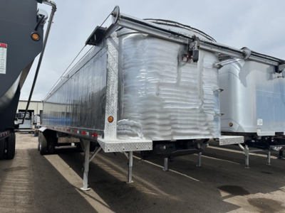 2018 Travis Vertex dump trailer side view showing aluminum conveyor-dented front corner and support legs.