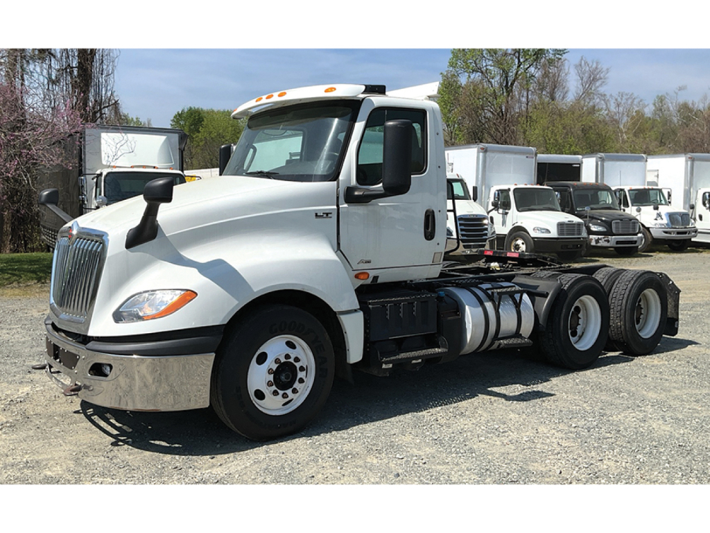 Truck cab chassis showing International LT Series 6x4 with front chrome bumper and fuel tanks, daytime outdoor lot.