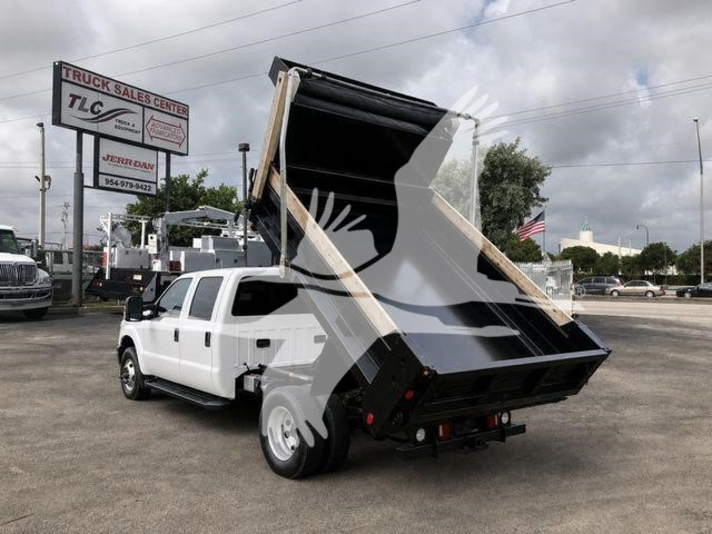 Ford F-350 dump truck with bed raised in a dealership lot.
