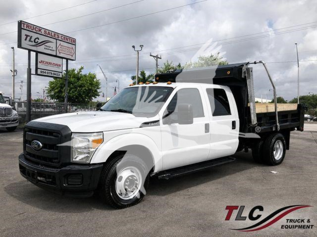 Ford F-350 dump truck in white with black grille, dual rear wheels, and dump bed. VIN 1FD8W3G69FED09275 visible; TLC Truck Sales Center sign in background.