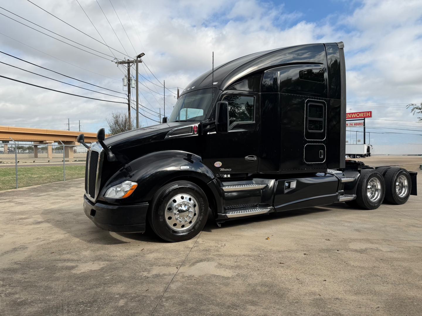 Kenworth T680 tractor-trailer cab in black, side view showing sleeper cab, chrome wheels, and aerodynamic mirrors.